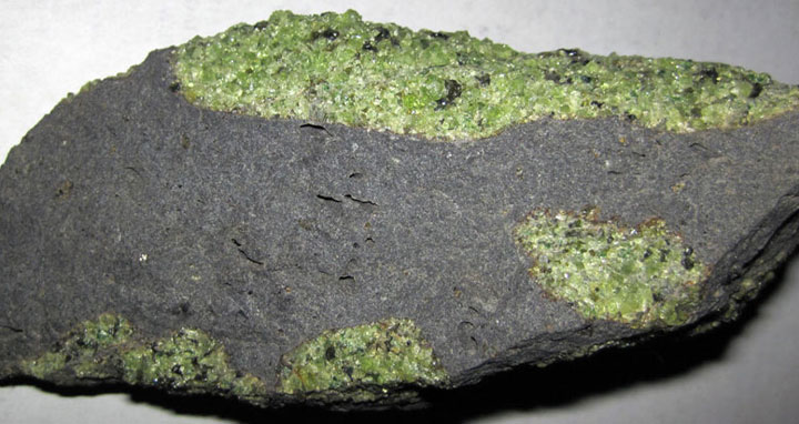 Olivine is the most abundant mineral in Earth’s upper mantle, which comprises the bulk of the planet’s tectonic plates. (Photo: Olivine xenoliths in basalt, John St. James/Flickr)